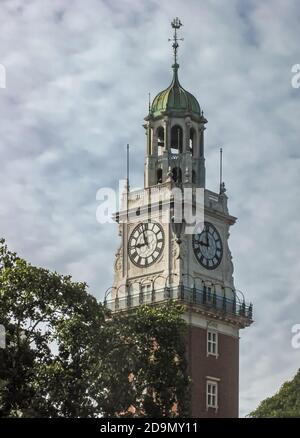 Buenos Aires, Argentina- December 19, 2008: Upper section of British naval clock tower against blue cloudscape with green folliage. Stock Photo