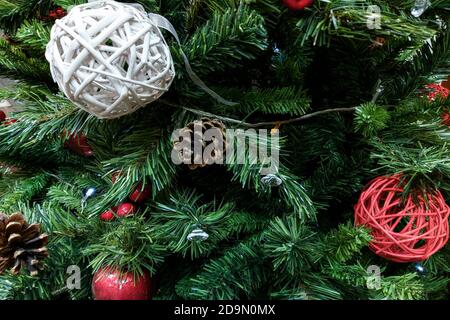 Fragment of a green New Year tree decorated with red and white New Year's toys and cones. Stock Photo