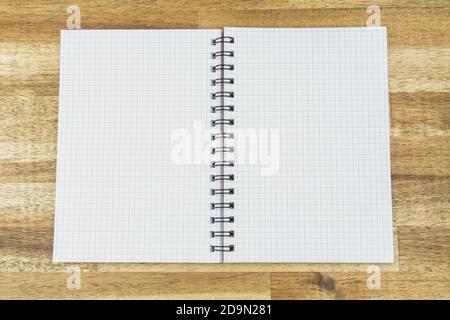 Opened notebook with squared lines on a wooden background Stock Photo