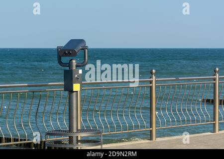 Public binoculars by sea. Coin-operated binocular viewer for tourists. Stock Photo