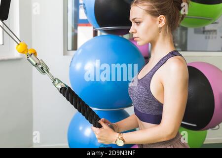Young European blond sporty girl does an exercise in a gym Stock Photo