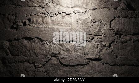 Grungy dark brick wall with plastering relief and spotlight illumination, background photo texture Stock Photo