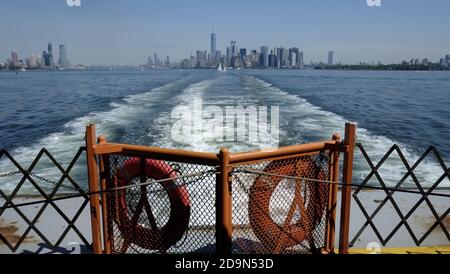 Wall Street office towers with One World Trade Center, designed by David Childs from Skidmiore, Owings & Merril, with Jersey City on left, photographed from Staten Island Ferry Stock Photo