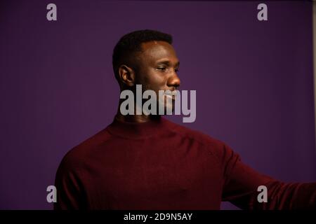 Profile portrait of black man with head turned to side. Isolated background. Medium shot. Stock Photo