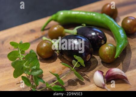 Harvesting aubergines and cooking them vegetarian: healthy and sustainable nutrition from your own garden. Freshly harvested vegetables on a wooden board. Stock Photo