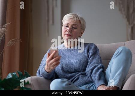 Senior woman waiting for a phone call at home Stock Photo