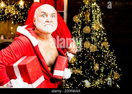 Santa Claus thief with a bag of christmas gifts. Home Burglar Santa Claus in a Mask Into the House. Best prices for winter gifts. Seasonal offer Stock Photo