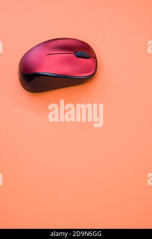 Vertical shot of a wireless mouse on an orange surface Stock Photo