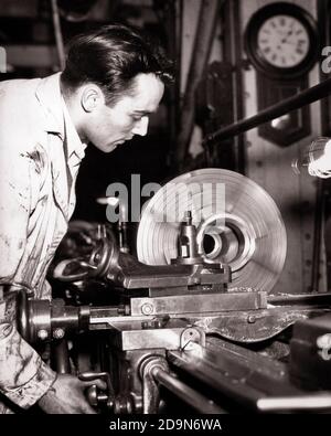 1930s YOUNG MAN MACHINIST WORKING IN MACHINE SHOP TOOL ROOM OPERATING A LATHE CUTTING METAL - i690 HAR001 HARS LABOR A IN EMPLOYMENT OCCUPATIONS LATHE EMPLOYEE PRECISION YOUNG ADULT MAN BLACK AND WHITE CAUCASIAN ETHNICITY HAR001 LABORING MACHINIST OLD FASHIONED Stock Photo