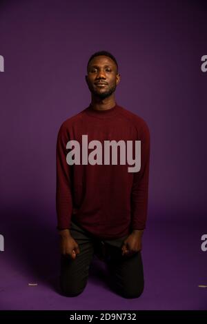 Young black man standing on knees looking at camera. Isolated background. Full length. Front view. Stock Photo