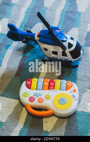 POZNAN, POLAND - Oct 27, 2018: Plastic toy music keyboard and helicopter laying on a carpet floor Stock Photo