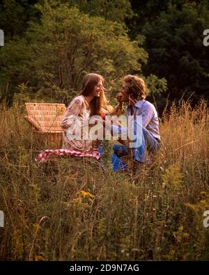 1970s LONG BLOND HAIR COUPLE ENJOYING PICNIC IN OUTDOOR FIELD - kc8560 PHT001 HARS PAIR ROMANCE COLOR RELATIONSHIP OLD TIME FIGURES NOSTALGIA OLD FASHION 1 STYLE BLOND YOUNG ADULT STRONG LIFESTYLE GROWNUPS FEMALES MARRIED RURAL SPOUSE HUSBANDS GROWNUP COPY SPACE FRIENDSHIP HALF-LENGTH LADIES PERSONS GROWN-UP CARING MALES PAIRS FOODS DATING HAPPINESS AND ENJOYING NUTRITION HAMPER PICNICS RELATIONSHIPS SMILES BLUE JEAN CONSUME CONSUMING GRASSES NOURISHMENT PICNICKING STYLISH PERSONAL ATTACHMENT AFFECTION COLORS EMOTION TOGETHERNESS WIVES YOUNG ADULT MAN YOUNG ADULT WOMAN CASUAL Stock Photo