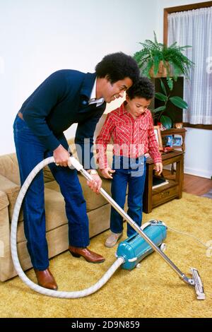 1980s FATHER AND SON VACUUM CLEANING GOLD SHAG CARPET  - kh7943 PHT001 HARS JUVENILE YOUNG ADULT COTTON SONS FAMILIES LIFESTYLE SATISFACTION HOME LIFE COPY SPACE FRIENDSHIP FULL-LENGTH PERSONS SHAG CARING MALES HOOVER DENIM FATHERS GOALS VACUUMING HAPPINESS CHORE DISCOVERY AFRICAN-AMERICANS AFRICAN-AMERICAN AND BONDING DADS KNOWLEDGE BLACK ETHNICITY PRIDE CONNECTION BLUE JEANS COOPERATION INFORMAL JUVENILES MID-ADULT MID-ADULT MAN TASK TOGETHERNESS TWILL YOUNG ADULT MAN CASUAL OLD FASHIONED SHAG CARPET AFRICAN AMERICANS Stock Photo