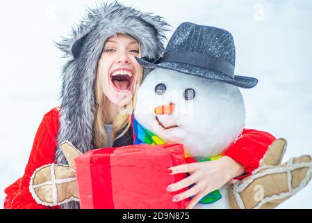 Enjoying nature wintertime. Well dressed enjoying the winter. Winter clothes for woman. Happy girl playing with a snowman on a snowy winter walk. Stock Photo