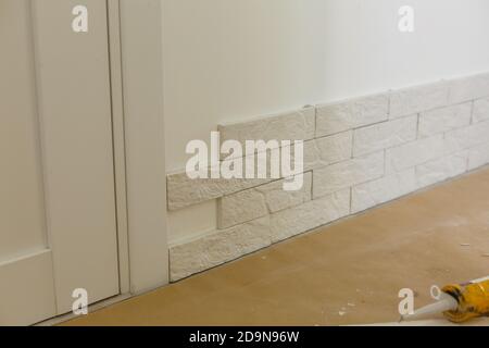 Professional Builder gluing decorative tile on wall. worker mounts decorative brick on wall Stock Photo