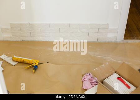 Professional Builder gluing decorative tile on wall. worker mounts decorative brick on wall Stock Photo