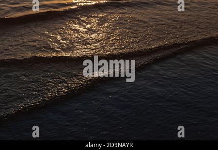 Natural background and glare on the surface of the sea. Small waves in otherwise calm water during the sunset time Stock Photo