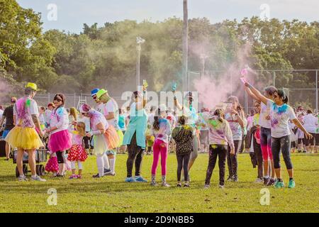 MACKAY, QUEENSLAND, AUSTRALIA - JUNE 2019: People throwing colored powder at each other at the start of Color Frenzy Fun Run in park Stock Photo