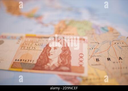 Ten thousand Colombian pesos bill below Colombia on a colorful and blurry map Stock Photo