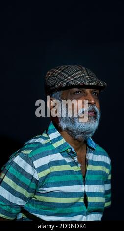 Vertical shot of a bearded Asian senior man wearing a stylish hat isolated on a black background Stock Photo
