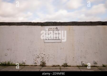 Sign on a white wall requesting minimum noise and no skateboarding or ball games Stock Photo