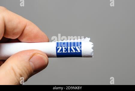 Paris, France - Oct 16, 2020: POV male hand holding isolated on gray background Zeiss microfiber cleaning cloths for eyewear, optics, screens Stock Photo