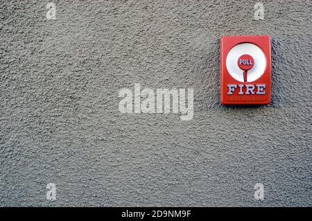 Manual fire alarm pull station on stucco wall. Stock Photo