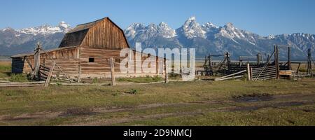 The old log barn and corrals on the John Moulton homestead on Mormon Row in Grand Teton National Park with the Teton Range behind.  Wyoming, USA. Stock Photo