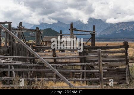 Old corrals and the granary of the John Moulton homestead on Mormon Row in Grand Teton National Park with the Teton Range behind.  Wyoming, USA. Stock Photo