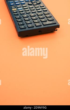 A top view closeup of a graphing calculator isolated on an orange background Stock Photo