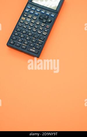 A top view closeup of a graphing calculator isolated on an orange background Stock Photo