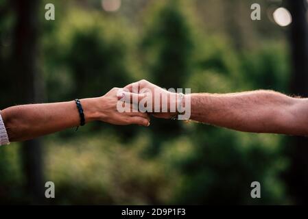 Concept of love and help each other people or relationship - close up of hands touching and holding or helping - green bokeh defocused background