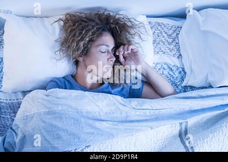 Beautiful adult caucasian lonely woman sleep alone in a double bed at home - concept of independence and portrait of people sleeping and relaxing - morning wake up concept Stock Photo