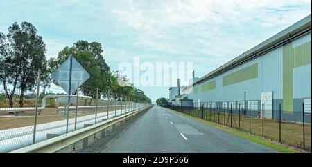 Brisbane, Queensland, Australia - 26th September 2019: A fenced road running the length of an industrial factory with a pipeline on one side Stock Photo