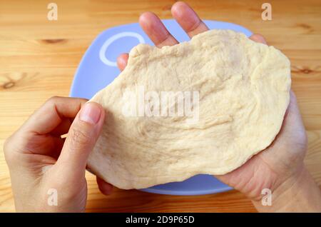 Man's hands stretching the dough for baking homemade bread Stock Photo
