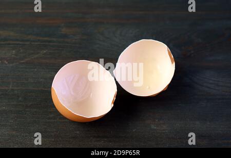 Cracked eggshells isolated on black wooden table Stock Photo