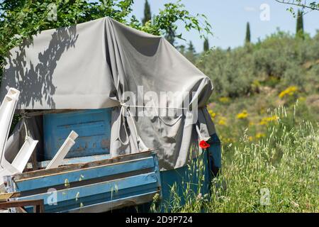 old and worn-down three-wheeler in a meadow of the Tuscan countryside Stock Photo