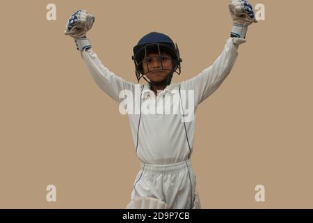 A boy in cricket uniform waving his arms in celebration Stock Photo