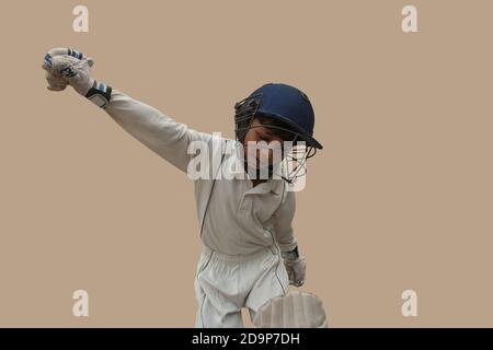 A boy in cricket uniform waving his arms in celebration Stock Photo