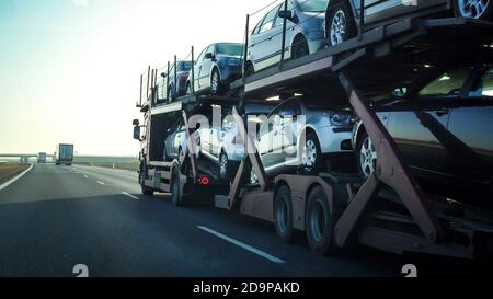 Car transporter trailer loaded with many cars on a highway, motion blur effect. Stock Photo