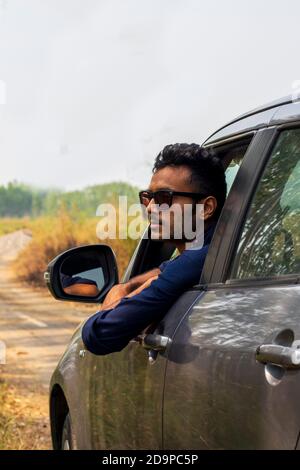 Portrait of young indian man looking outside on car window Stock Photo