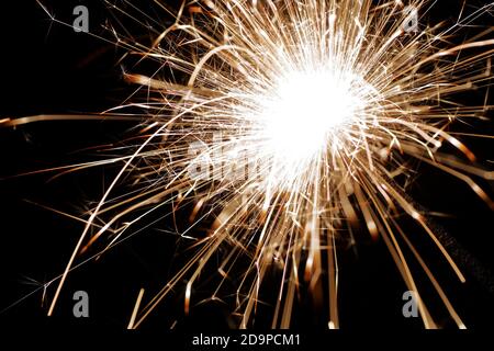 Closeup burning sparkler. Bengal light - type of hand-held firework that burns slowly while emitting flames and sparks. Stock Photo