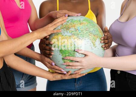 A large globe with all continents is supported by female hands of various races, symbolizing unity, acceptance and racial tolerance. Stock Photo