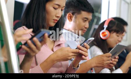 Young people using mobile phone in public underground train . Urban city lifestyle and commuting in Asia concept . Stock Photo