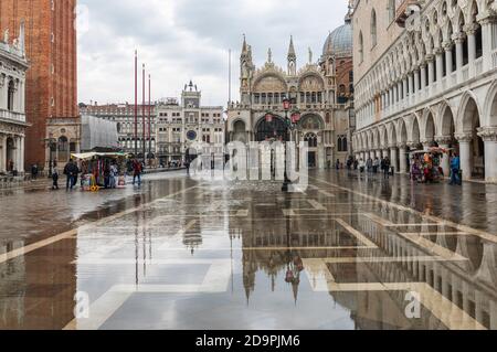 Acqua Alta causing flooding in Piazza San Marco. St Marks Basilica and The Doges Palace reflected in the water. St Marks Square, Venice, Italy Stock Photo