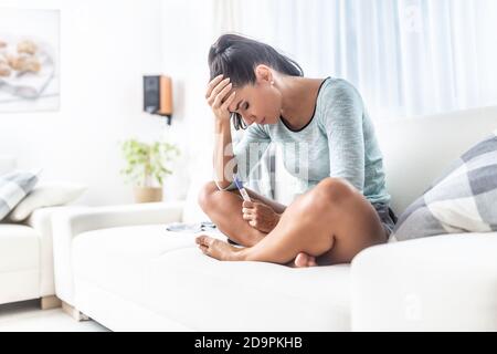 Woman holding her head thinking about abortion after finding out she is pregnant from a test.