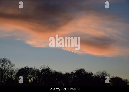 Cirrus type clouds tinged with colour from the setting sun highlighting shapes and patterns across the sky. Stock Photo