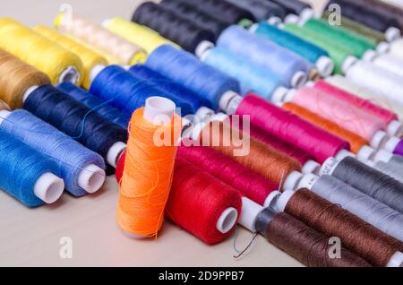 Flat lay of many spools with colorful threads on wooden desk or table, home crafting, indoors, close-up Stock Photo