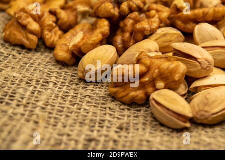 Pistachios and walnuts lie on the sacking. Close up Stock Photo