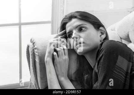 Studio portrait of young beautiful woman laying on sofa Stock Photo